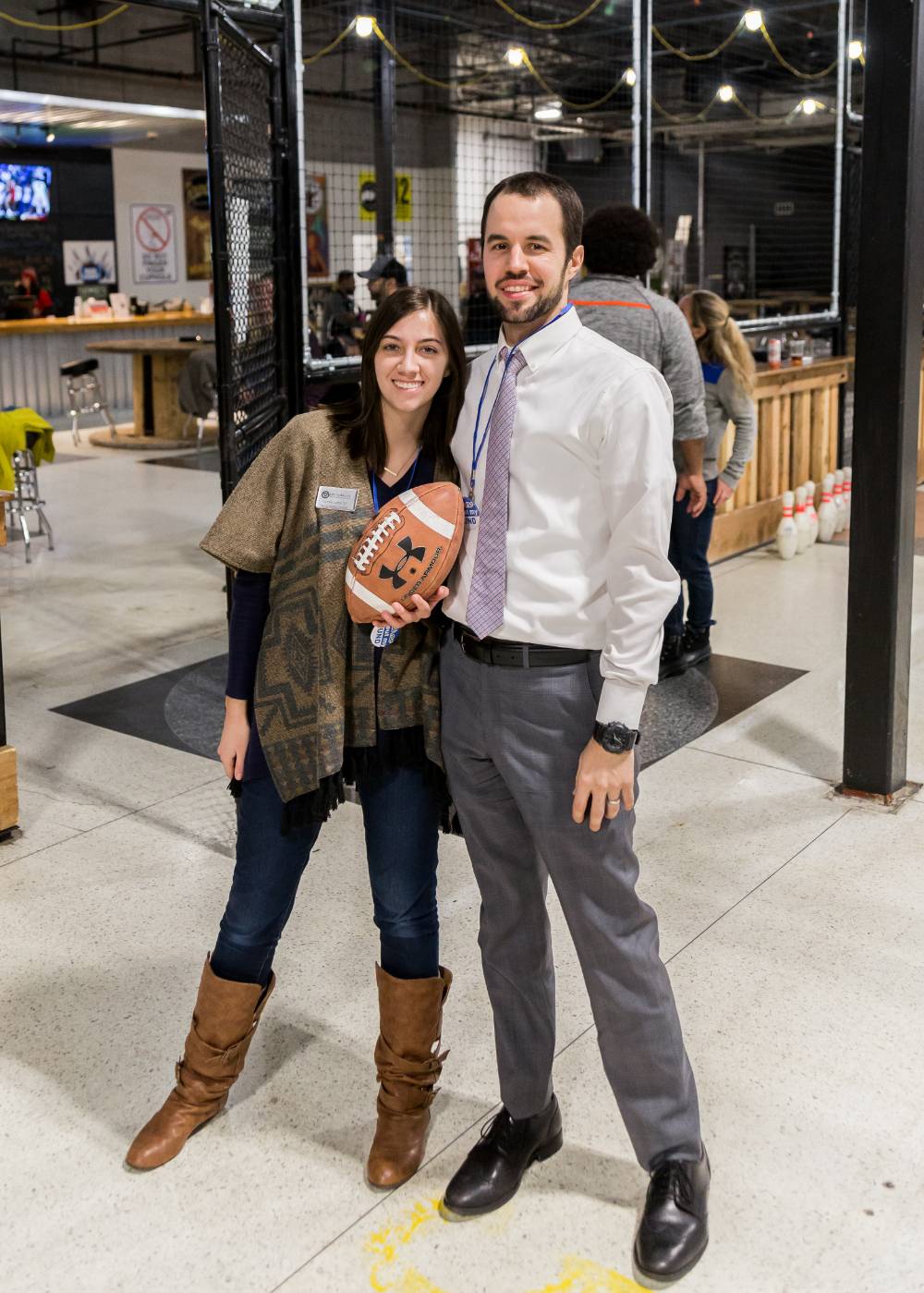 Two alumni pose holding a football at the Fowling Fun Event